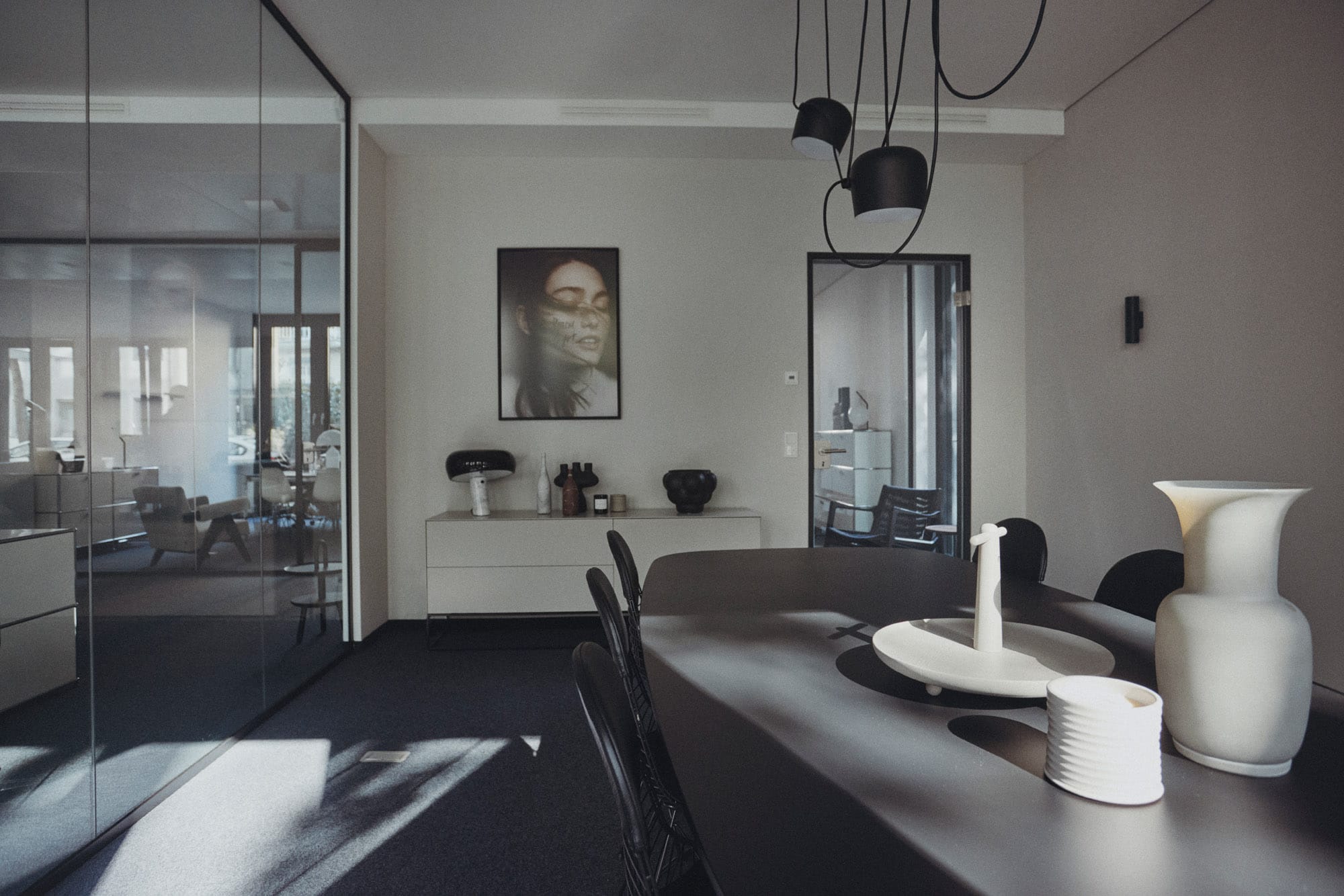 Modernes Büro-Interieur mit dunklem Konferenztisch, Designerleuchten und dekorativen Vasen